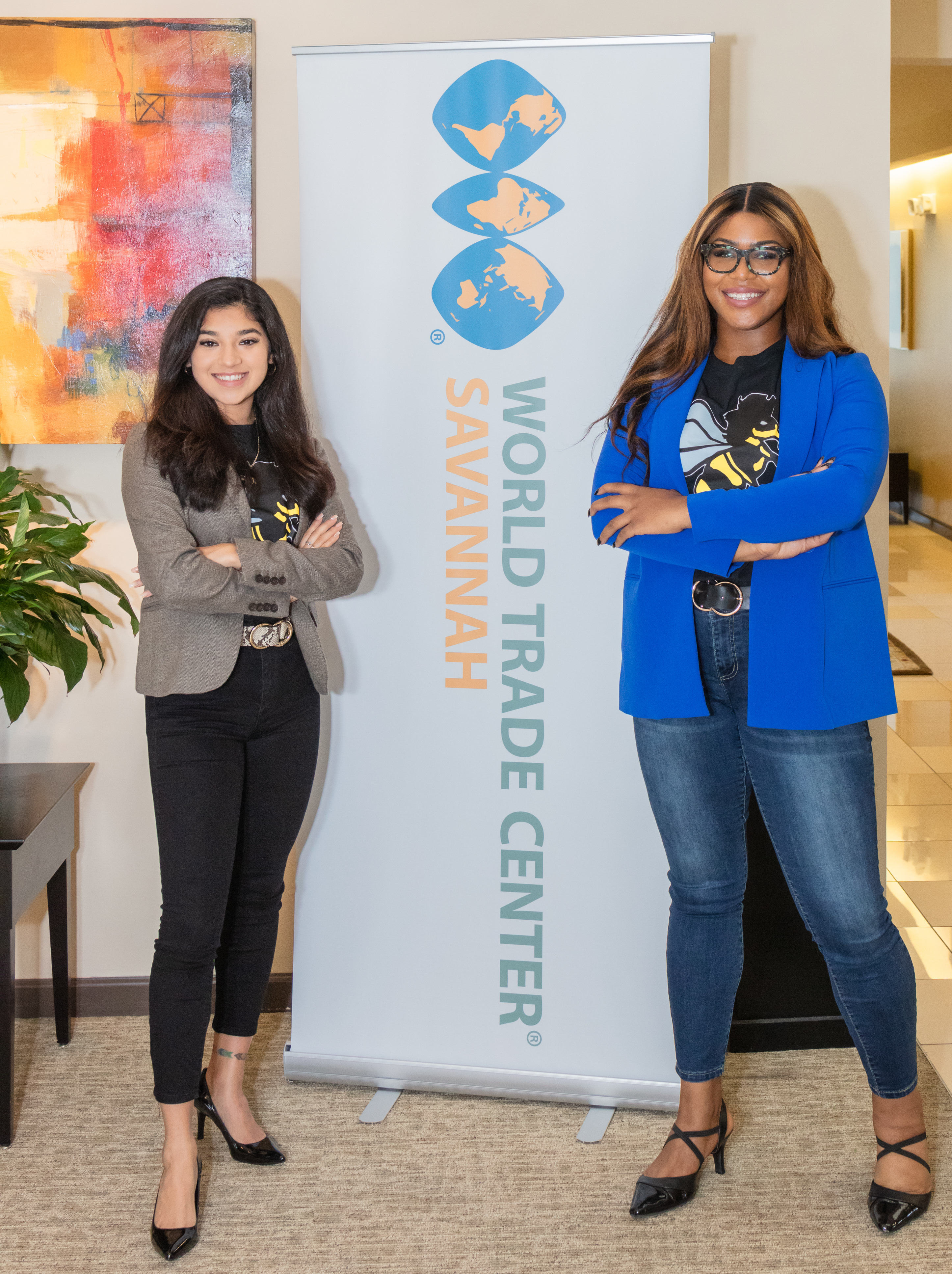 Two women standing in front of a banner with the text World Trade Center Savannah on it