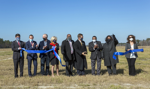 People cutting a ribbon out in a field