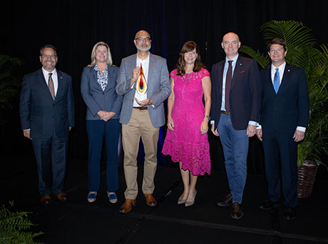 Group of men and women holding an award smiling